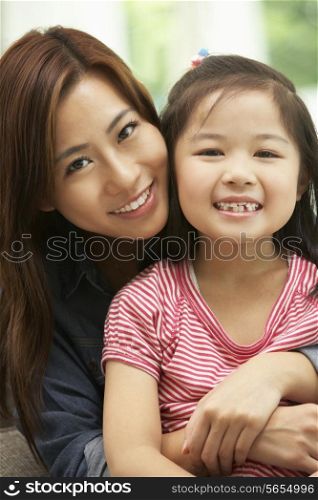 Chinese Mother And Daughter Sitting On Sofa At Home Together