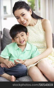 Chinese Mother And Son Sitting On Sofa At Home Together