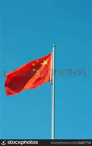 Chinese national five-star red flag fluttering in the wind against blue sky