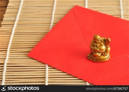Chinese New Year design. A red envelope for money in the Chinese New Year isolated on a wooden background with a Buddha
