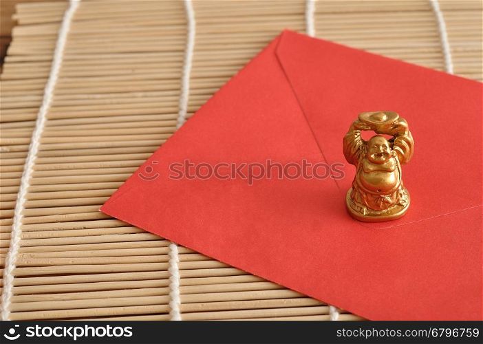 Chinese New Year design. A red envelope for money in the Chinese New Year isolated on a wooden background with a Buddha