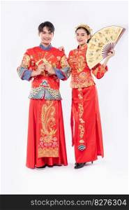 Chinese new year man and woman wear cheongsam with gift money and hand fan