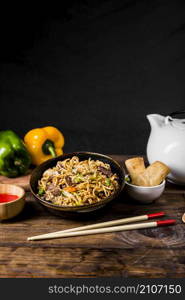 chinese noodles with beef vegetables served with spring rolls wooden desk