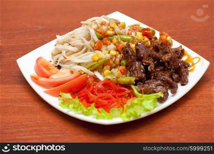chinese noodles with roasted meat and vegetables. plate of chinese noodles with roasted meat and vegetables