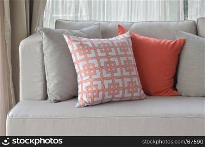 Chinese pattern in orange with deep orange and gray pillows on light gray sofa set