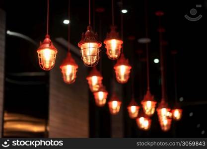 Chinese red metal chandeliers hang from the ceiling of luxury hotel, many lamps. Interior decoration.