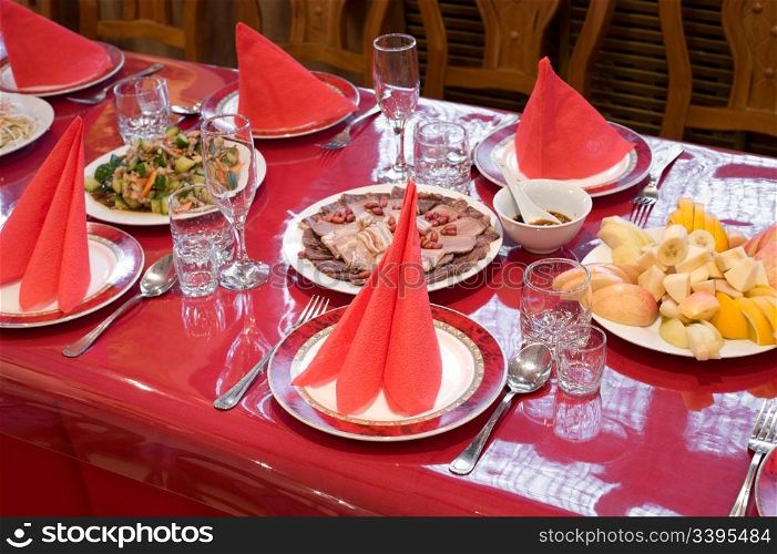 chinese restaurant laid table with bright red glossy tablecloth