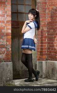 Chinese schoolgirl in front of red brick school building