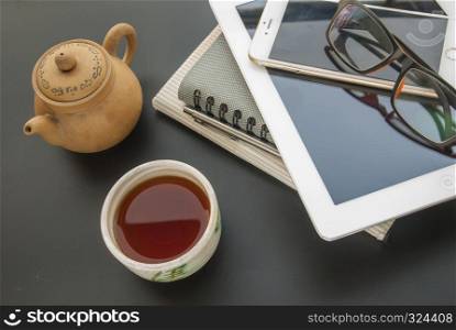 Chinese tea prepared to drink to relax from working with cameras, glasses, mobile phones, car keys, pens and notebooks.