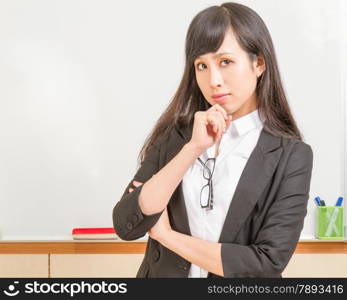 Chinese teacher in front of whiteboard dressed formal, deep in thought