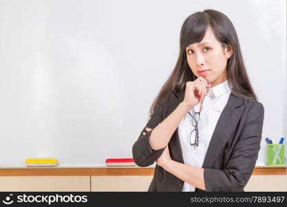 Chinese teacher in front of whiteboard dressed formal, deep in thought