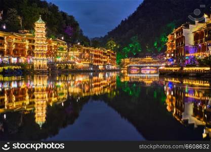 Chinese tourist attraction destination - Feng Huang Ancient Town  Phoenix Ancient Town  on Tuo Jiang River illuminated at night. Hunan Province, China. Feng Huang Ancient Town  Phoenix Ancient Town  , China