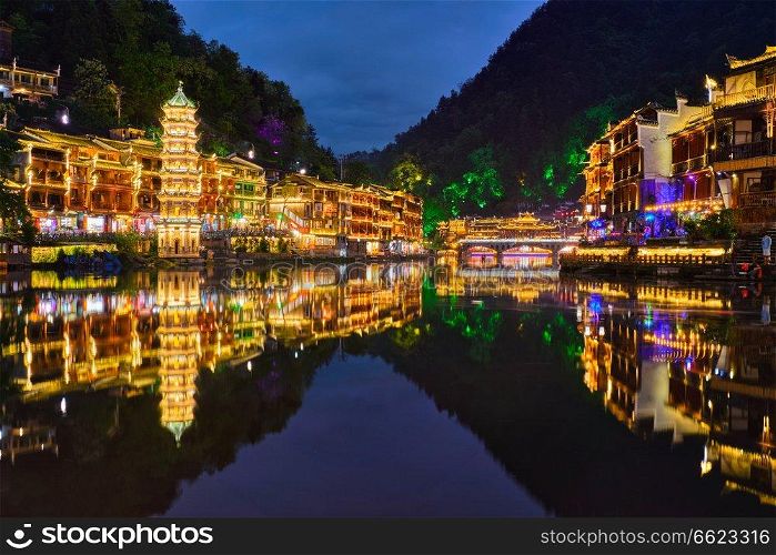 Chinese tourist attraction destination - Feng Huang Ancient Town (Phoenix Ancient Town) on Tuo Jiang River illuminated at night. Hunan Province, China. Feng Huang Ancient Town Phoenix Ancient Town , China