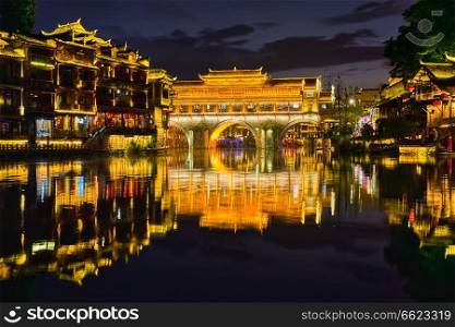 Chinese tourist attraction destination - Feng Huang Ancient Town  Phoenix Ancient Town  on Tuo Jiang River illuminated at night. Hunan Province, China. Feng Huang Ancient Town Phoenix Ancient Town , China