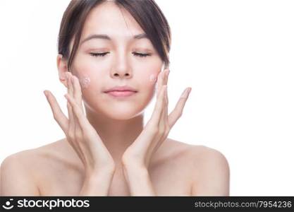 Chinese woman applying cream to face, skincare concept