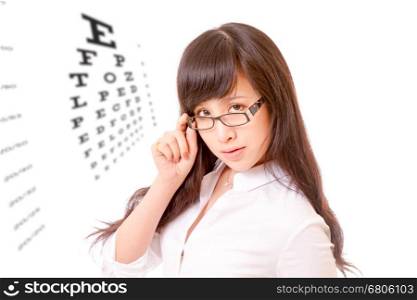 Chinese woman peering over the top of her spectacles, with eyesight test chart