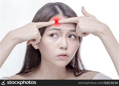 Chinese woman squeezing a glowing red spot on her forehead, desaturated