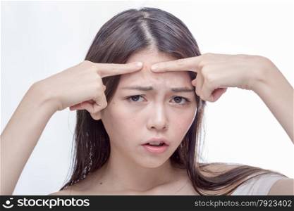 Chinese woman squeezing a spot on her forehead
