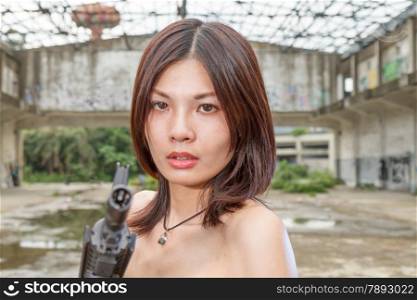 Chinese woman with sub-machine gun by abandoned building