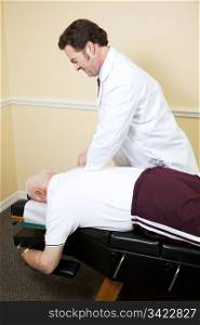 Chiropractor adjusts a senior man&rsquo;s spine on his examining table.