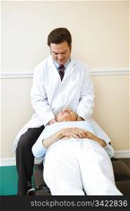 Chiropractor adjusts an elderly female patient&rsquo;s cervical spine (neck).