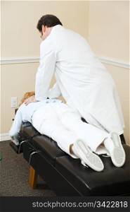 Chiropractor aligning a patient&rsquo;s vertebrae in his office.
