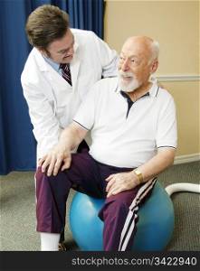 Chiropractor does physical therapy with a senior man, using a pilates ball.