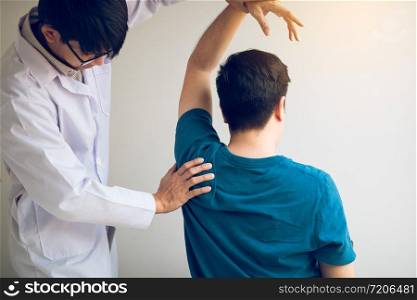 Chiropractor stretching a young man arm in medical office