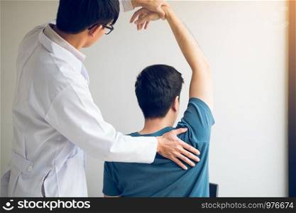 Chiropractor stretching a young man arm in medical office