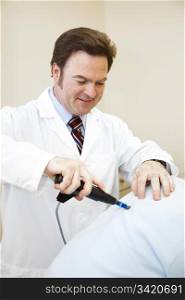 Chiropractor using a digital tool to adjust a patient&rsquo;s back.