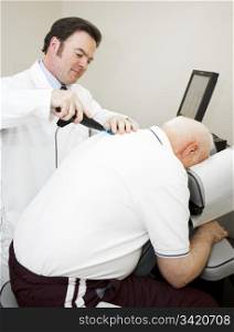 Chiropractor using a modern, electronic tool to adjust and elderly patient&rsquo;s back.