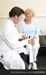 Chiropractor with a senior patient, looking at a model of the human spine.