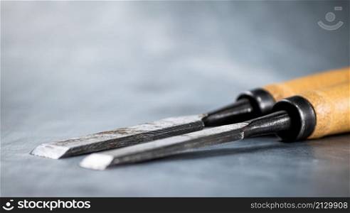 Chisel on wood on the table. On a gray background. High quality photo. Chisel on wood on the table.