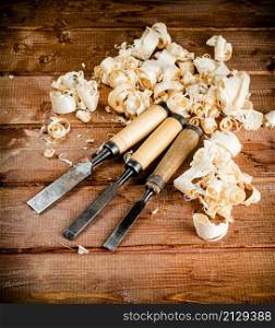 Chisel with a bunch of wood sawdust. On a wooden background. High quality photo. Chisel with a bunch of wood sawdust.