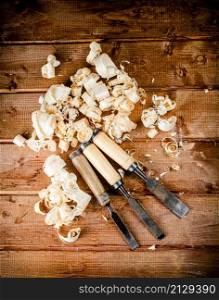 Chisel with a bunch of wood sawdust. On a wooden background. High quality photo. Chisel with a bunch of wood sawdust.