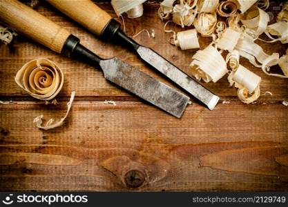 Chisels with wood chips on the table. On a wooden background. High quality photo. Chisels with wood chips on the table.