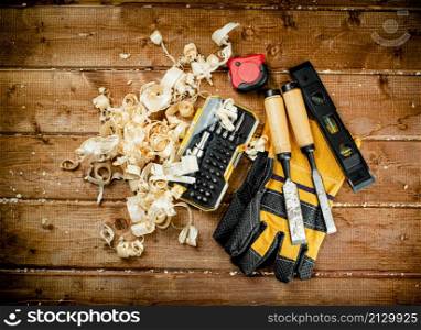 Chisels with wooden sawdust on the table. On a wooden background. High quality photo. Chisels with wooden sawdust on the table.