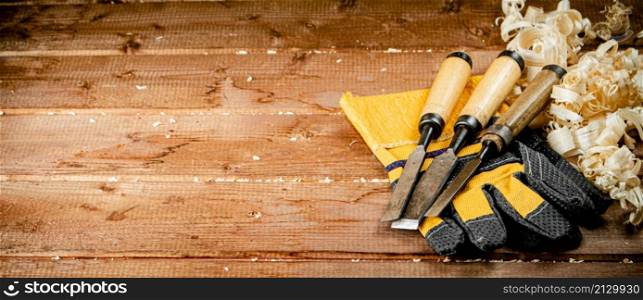Chisels with wooden sawdust on the table. On a wooden background. High quality photo. Chisels with wooden sawdust on the table.