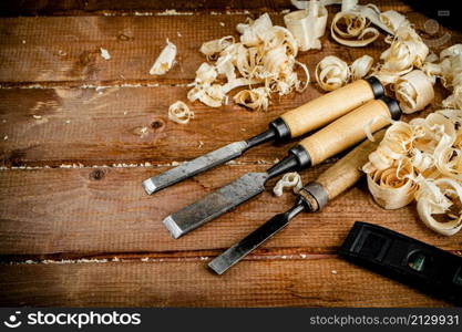 Chisels with wooden sawdust on the table. On a wooden background. High quality photo. Chisels with wooden sawdust on the table.