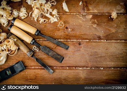 Chisels with wooden sawdust on the table. On a wooden background. High quality photo. Chisels with wooden sawdust on the table.