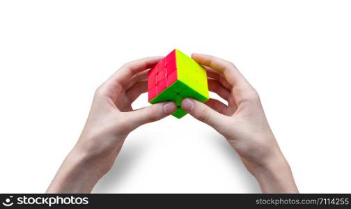 CHISINAU, MOLDOVA - September 1, 2019: Young male hand holding colorful Rubik?s cubes on white background. Rubik?s Cube was invented in 1974 by Hungarian sculptor and professor Erno Rubik. Concept of idea and puzzle construction. With clipping path