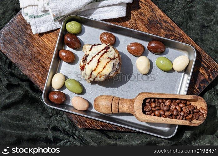 Chocobon (Soft chocolate bun) topped with rich cream cheese frosting and Cinnamon served with assorted almond nuts chocolate in stainless tray with dark background. Top view, Space for text, Selective focus.