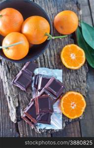 chocolate and tangerines on the wooden board and on a table
