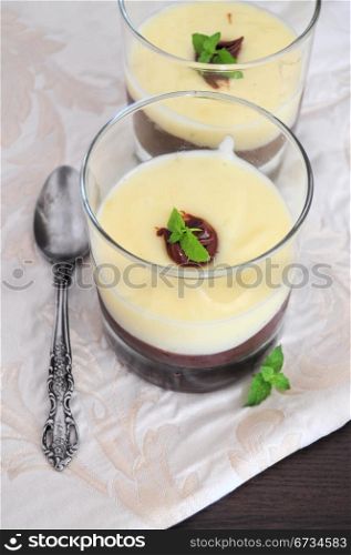 Chocolate and vanilla cream, served in glasses, decorated with mint leaf