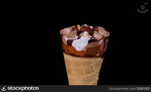 Chocolate and vanilla ice cream in cone rotating on black background.