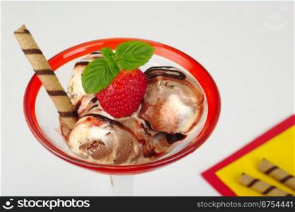 Chocolate and vanilla ice-cream scoops with strawberry, mint leaf, waffle roll, strawberry and chocolate syrup (Selective Focus). Ice-Cream with Strawberry and Mint Leaf