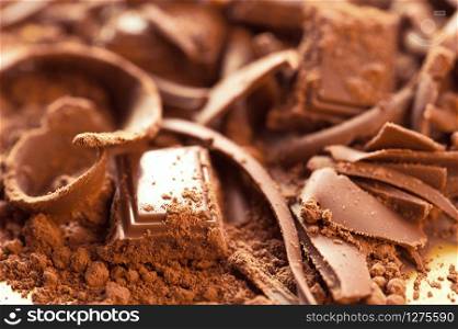 Chocolate background. Bars and strips of chocolate with cocoa powder. Shallow depth of field