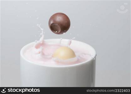 chocolate ball falling into a cup of strawberry milkshake