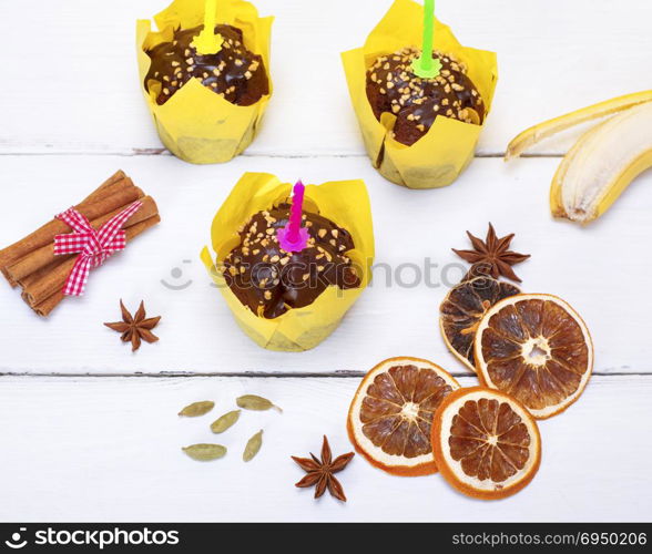 chocolate banana muffins with a candle on a white wooden background, top view