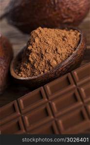 Chocolate bar, candy sweet, cacao beans and powder on wooden bac. Aromatic cocoa and chocolate on wooden background